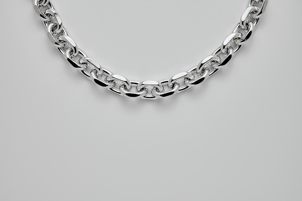 Polished stainless steel cable chain necklace on a pale grey background