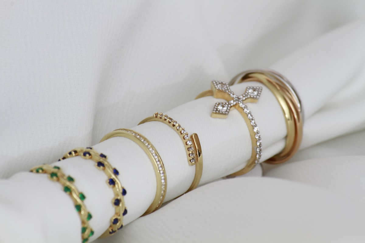 Bracelets joncs dorés et sertis de pierres posés sur un rouleau de tissu blanc
