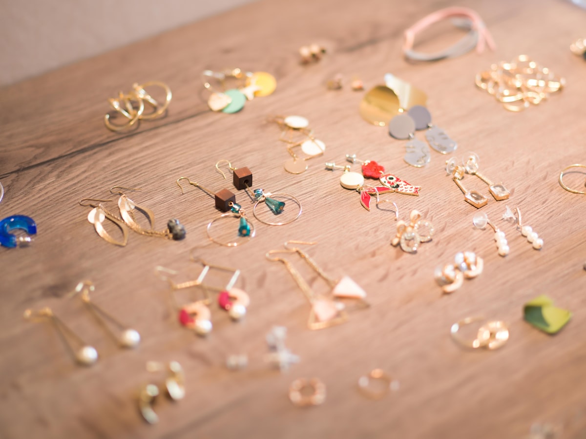 Dozens of earring pairs laid out on a wooden table, as seen when selecting stock at a wholesale showroom