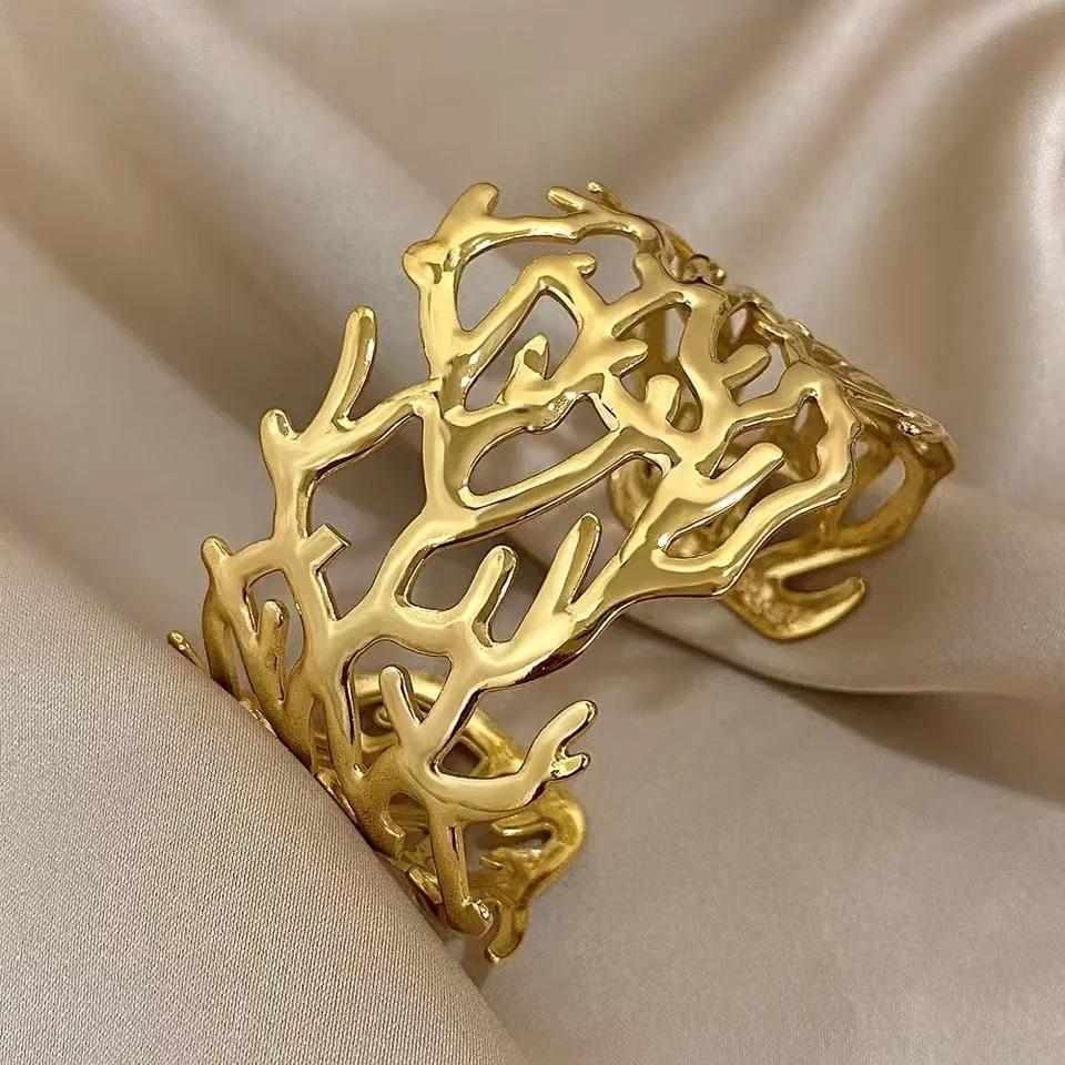Foto del producto: Brazalete rígido con motivo de ramas caladas, acero chapado en oro