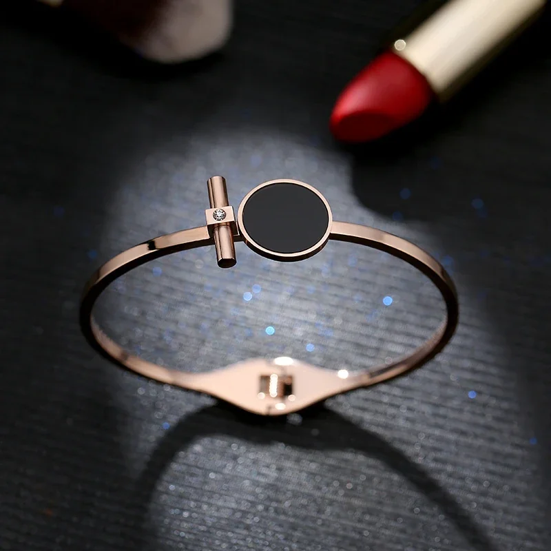 Foto del producto: Brazalete rígido con disco redondo negro y barra, acero chapado en oro