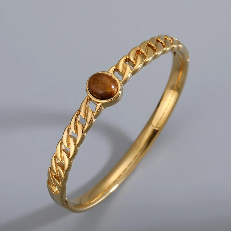 Foto del producto: Brazalete rígido con cristal ovalado marrón y acero chapado en oro