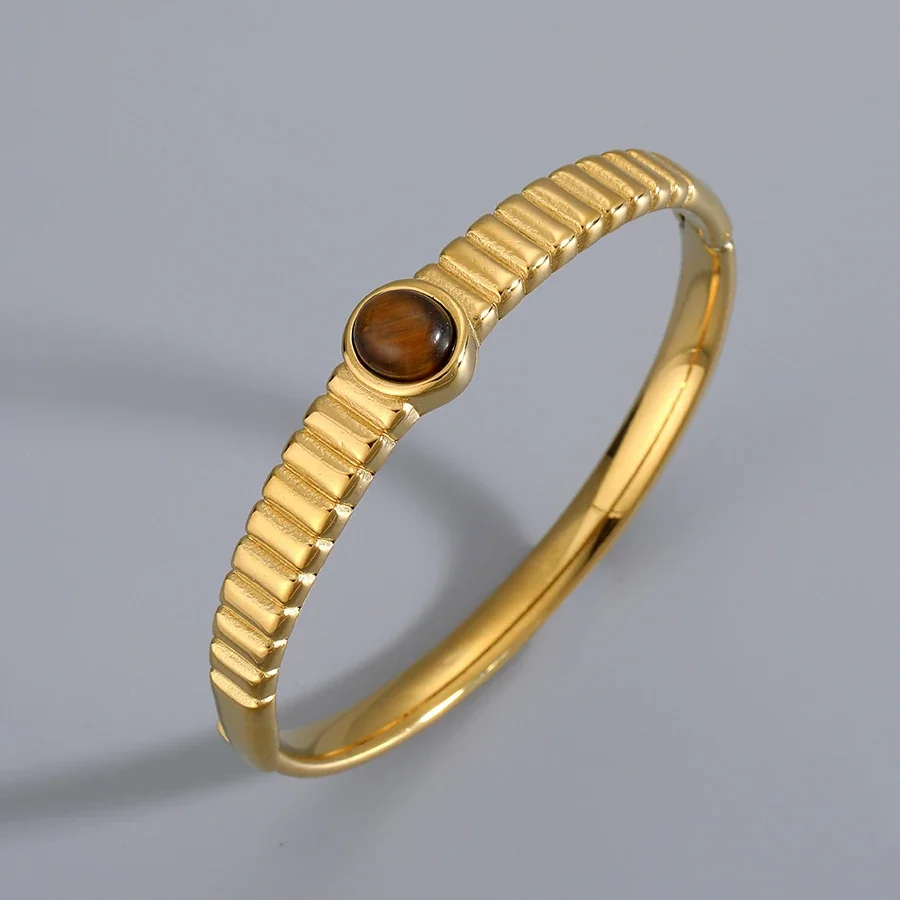 Foto del producto: Brazalete rígido con cristal ovalado marrón y acero chapado en oro
