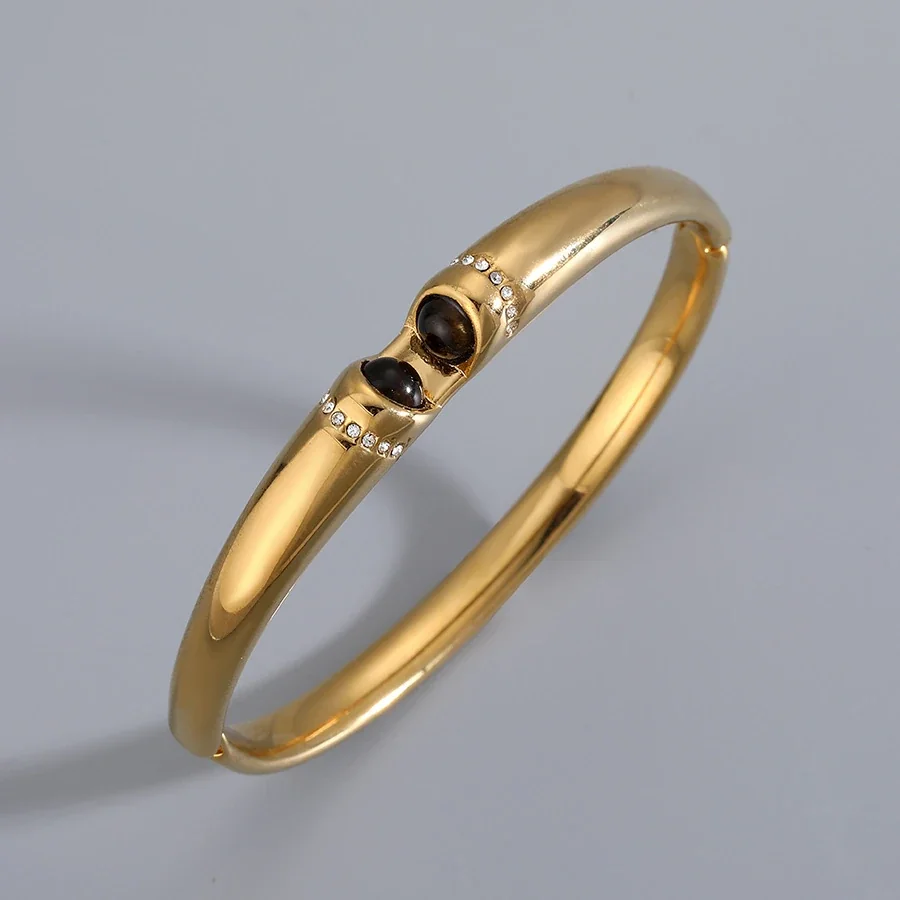Foto del producto: Brazalete rígido con cristal ovalado marrón y acero chapado en oro