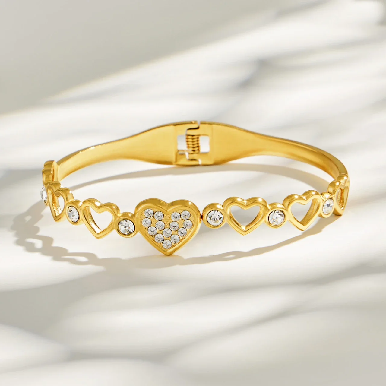 Foto prodotto: Bracciale rigido con maglie a cuore e zirconia cubica in acciaio inox 316 color oro
